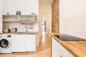 Eine moderne Küche mit Waschmaschine, Holz Arbeitsplatte und Ziegelwand.