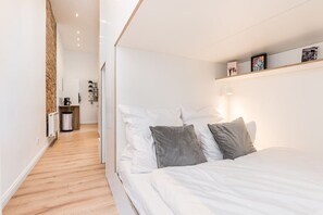 Ein Schlafzimmer mit einem Bett, einem Nachttisch, einem Regal mit Bildern und einer Heizung.