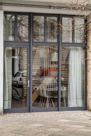 A modern building with a large glass door, a bicycle parked outside, and a table with chairs inside. - Stylish New Cube Loft by Berlin Wall Apartments (Berlin)