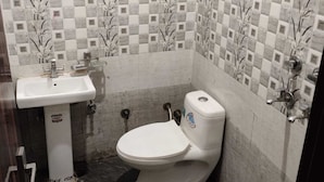 A bathroom with a sink, toilet, and shower. The walls have a checkered tile pattern with floral designs.