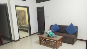 A living room with a sofa, a coffee table, and a bed in the background.