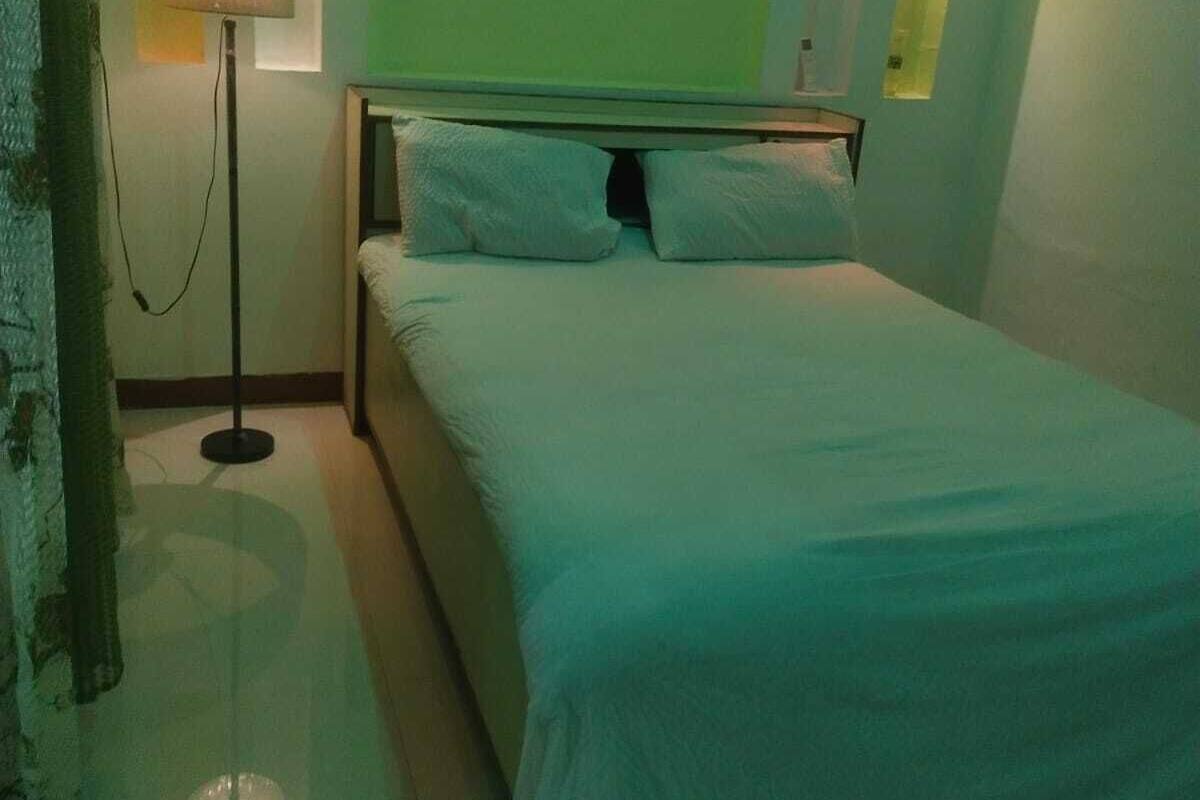 A bedroom with a bed, a bedside lamp, and wall-mounted lights.