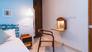 Une chambre à coucher comprenant un lit, une table de chevet, une chaise, une lampe de chevet et une étagère fixée au mur.