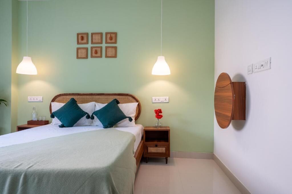 A neatly arranged bedroom with a bed, bedside tables, a wall-mounted mirror, and a wall with framed pictures.