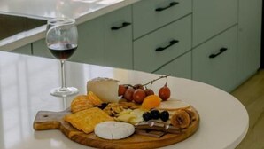 Una cocina con una isla redonda, una copa de vino y una tabla de fiambres.