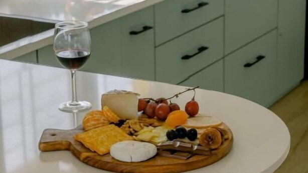 Une cuisine avec un îlot central rond, un verre à vin et une planche à charcuterie.