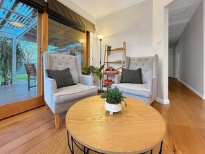 Ein Wohnzimmer mit zwei grauen Sofas, einem runden Holztisch und einem Bücherregal.