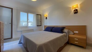 A bedroom with a bed, bedside tables, a dresser, a window, and wall-mounted lights. - HOUSE WITH COMUNITY POOL (l'Escala)