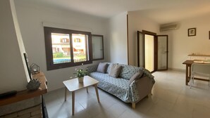 A living room with a sofa, a small table, a window, and a door. - HOUSE WITH COMUNITY POOL (l'Escala)