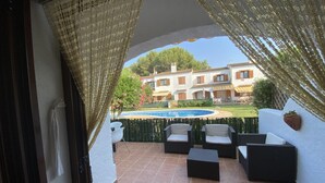 A patio with outdoor furniture, a swimming pool, and a building in the background. - HOUSE WITH COMUNITY POOL (l'Escala)