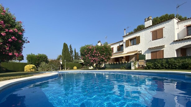 A clear swimming pool surrounded by a well-maintained garden with various plants and trees. - HOUSE WITH COMUNITY POOL (l'Escala)