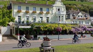 A hotel with a balcony, a sign reading 'Hotel Schön,' and a view of vineyards in the background. - Hotel Schön (Ruedesheim am Rhein)