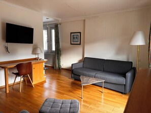 A living room with a sofa, a wooden desk, a chair, a small table, and a floor lamp. - Hotel Schön (Ruedesheim am Rhein)