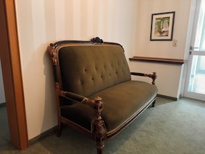 Un sofá de estilo vintage con patas de madera ornamentadas y un respaldo acolchado, situado frente a una pared con diseño a rayas.