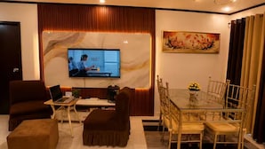 A living room with a TV, sofa, ottoman, and dining table with chairs.