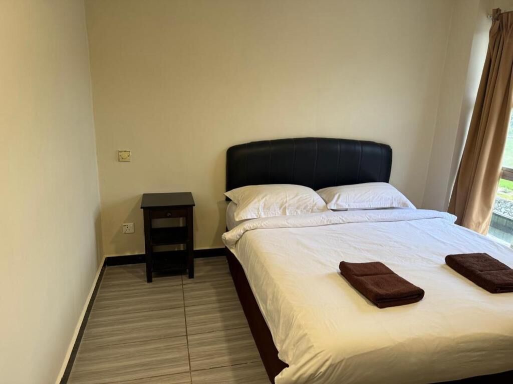A hotel room with a bed, a nightstand, and a window with curtains.
