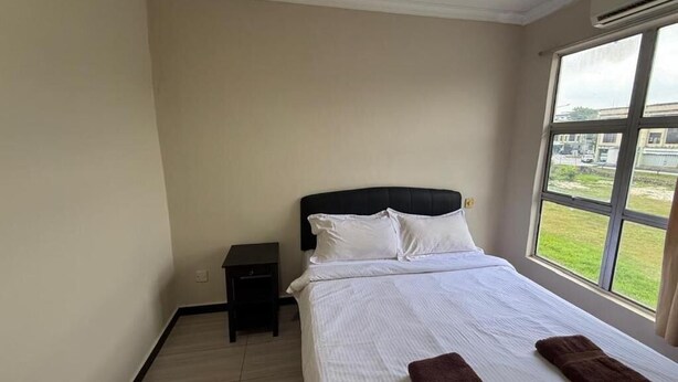 Quarto com cama, mesa de cabeceira, janela com vista e aparelho de ar condicionado.