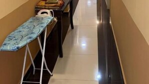 Corredor de hotel com um banco, tábua de passar roupa e espelhos fixados na parede.