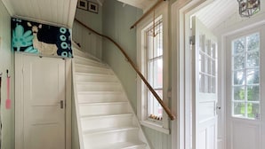A staircase with white steps, a wooden handrail, and a door with a window. - 4 Person Holiday Home in Aneby (Aneby)