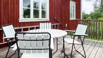 A red wooden deck with a white table and four chairs.
