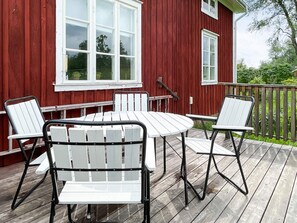 A red wooden deck with a white table and four chairs. - 4 Person Holiday Home in Aneby (Aneby)