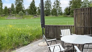 A wooden deck with a table and chairs, surrounded by a wooden fence, overlooking a grassy field. - 4 Person Holiday Home in Aneby (Aneby)