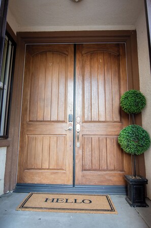 A wooden double door with a doormat that reads 'HELLO' and two small potted plants on either side. - Beautiful 4 Bedroom - Fun Family Pet Friendly Home (Lancaster)