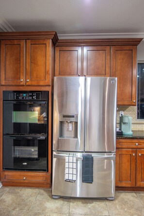 A kitchen with wooden cabinets, a stainless steel refrigerator, a built-in oven, and a coffee maker. - Beautiful 4 Bedroom - Fun Family Pet Friendly Home (Lancaster)