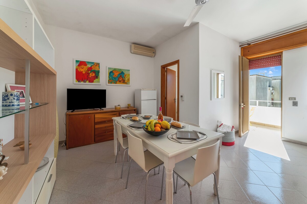 A modern kitchen with a dining area, a TV, and artwork on the walls.