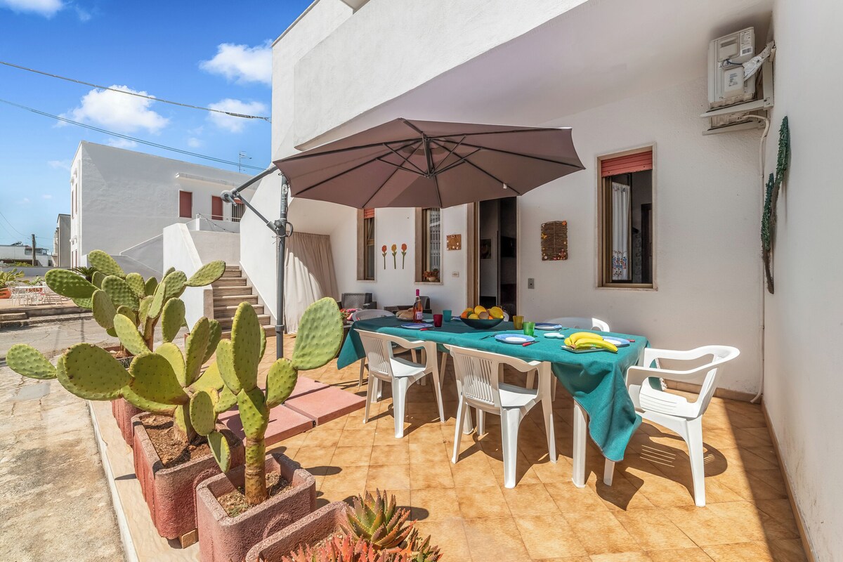 A patio with a table, chairs, and a large umbrella.