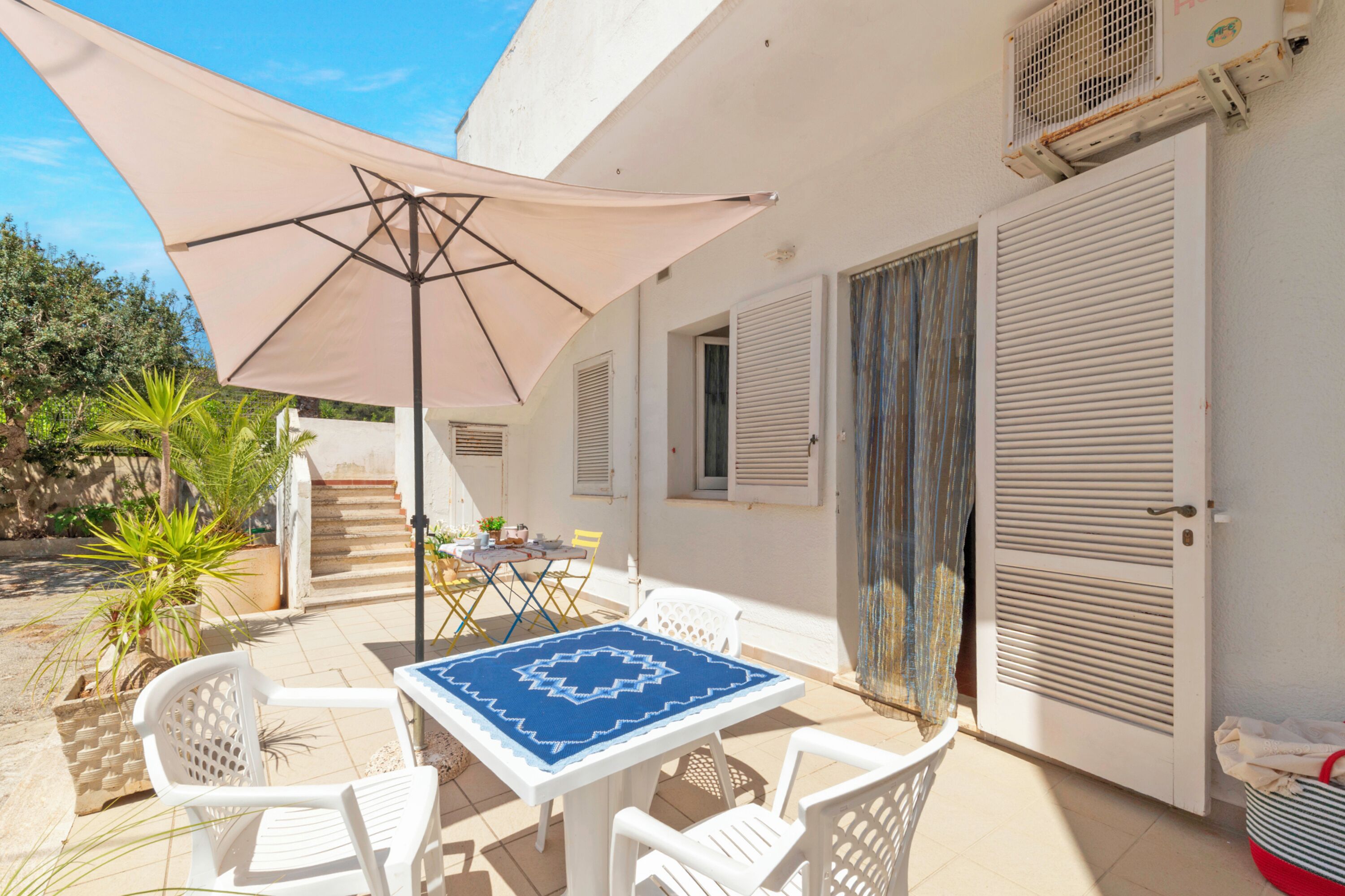 Eine Terrasse mit Tisch, Stühlen und einem großen Sonnenschirm.