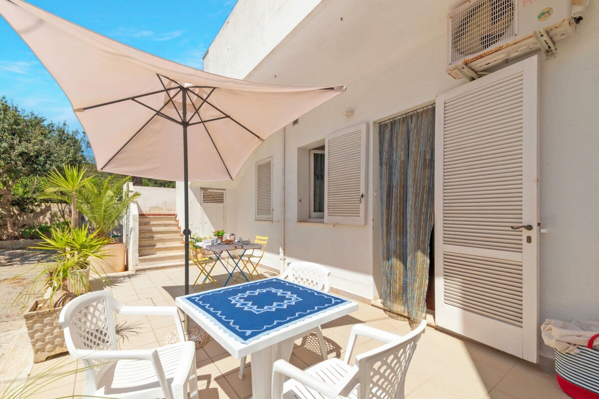 A patio with a table, chairs, and a large umbrella.