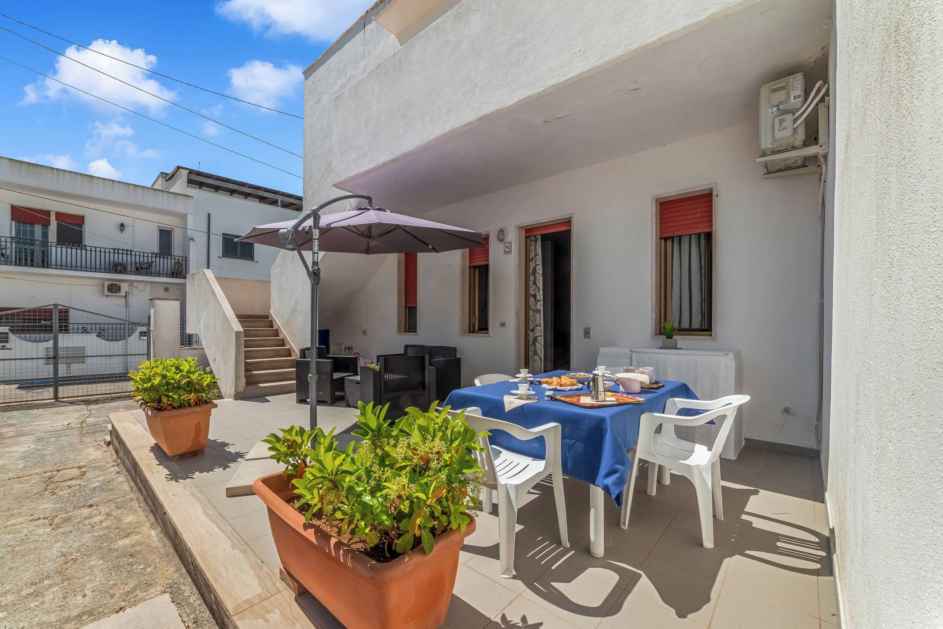 Eine Dachterrasse mit Esstisch, Topfpflanzen und einer Treppe zu einer oberen Ebene.