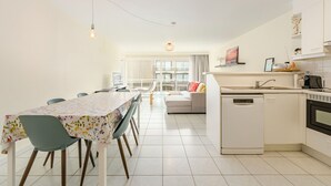 Eine moderne Küche mit Geschirrspüler, ein Essbereich mit Tisch und Stühlen sowie eine Wohnarea mit einer Couch.