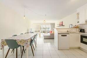 Eine moderne Küche mit Geschirrspüler, ein Essbereich mit Tisch und Stühlen sowie eine Wohnarea mit einer Couch.