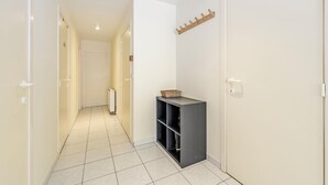 Ein Flur mit Heizkörper, schwarzem Stauraum und Kleiderhaken.