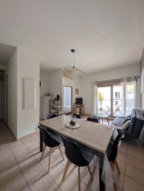 Ein modernes Wohnzimmer mit Essbereich, Fernseher und großem Fenster.