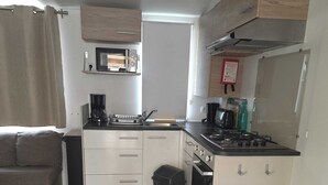 A compact kitchen with a microwave, toaster, sink, and stove. - Air-conditioned mobile home for 6–8 people—direct beach access at a 4-star comfort campground (Canet-en-Roussillon)