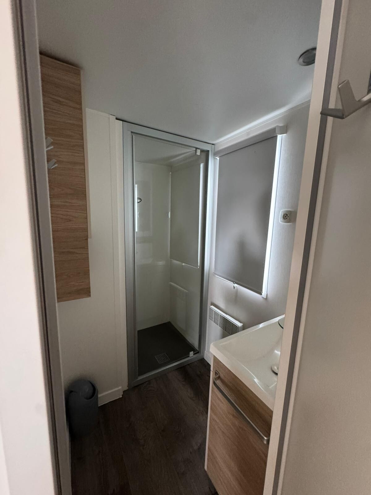 Una habitación compacta con armario de puerta corredera, una pequeña zona de ducha y un radiador empotrado.