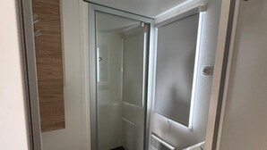 A compact room with a sliding door closet, a small shower area, and a built-in radiator. - Air-conditioned mobile home for 6–8 people—direct beach access at a 4-star comfort campground (Canet-en-Roussillon)