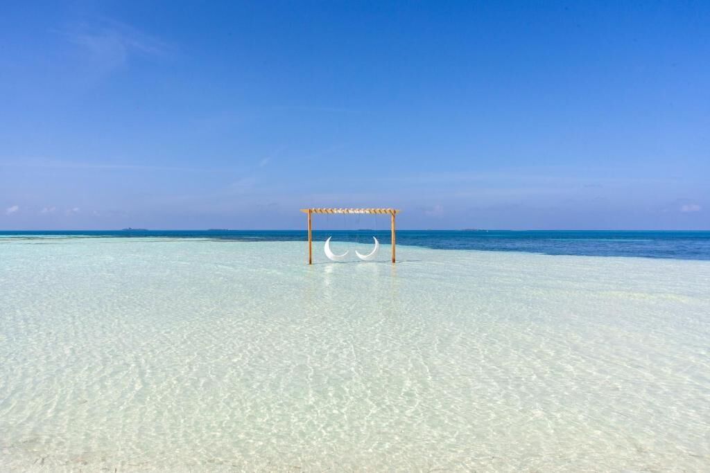 Una playa con agua turquesa cristalina y una estructura de madera en el centro.