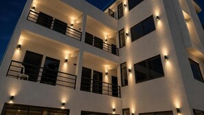 Un edificio de varios pisos con balcones e iluminación exterior.