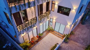 Un edificio moderno con patio en la azotea, ventanas amplias y plantas colgantes.