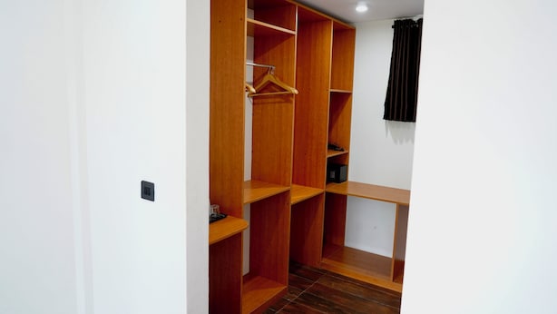 Un vestidor con varios estantes de madera y una barra para colgar.