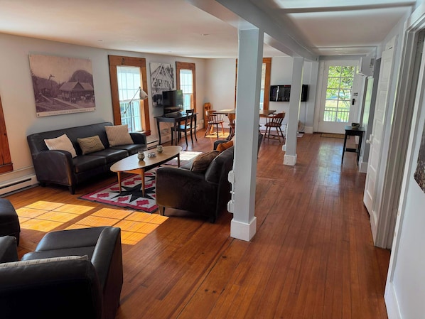 A spacious living room with a sofa, coffee table, and dining area. - The Rosendale Roost (Kingston)