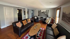 A living room with a black leather sofa, a wooden coffee table, and a patterned rug.