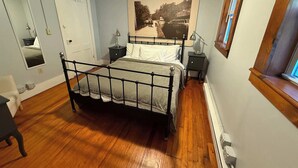 A bedroom with a bed, bedside tables, a mirror, a window, and a wall-mounted picture. - The Rosendale Roost (Kingston)