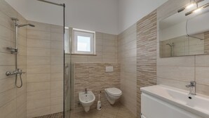 Un bagno moderno con doccia, bidet, WC e vasca da bagno.
