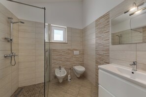 A modern bathroom with a shower, bidet, toilet, and bathtub. - Wabi Sabi Apartment 8 (Krk)