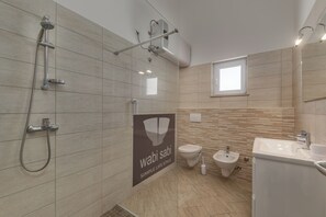 A modern bathroom with a shower, toilet, bidet, and sink. - Wabi Sabi Apartment 7 (Krk)